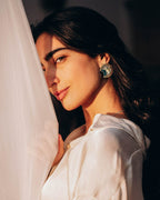 Woman wearing Sterling silver Eye of Horus earrings with protective symbolism and textured geometric accents.