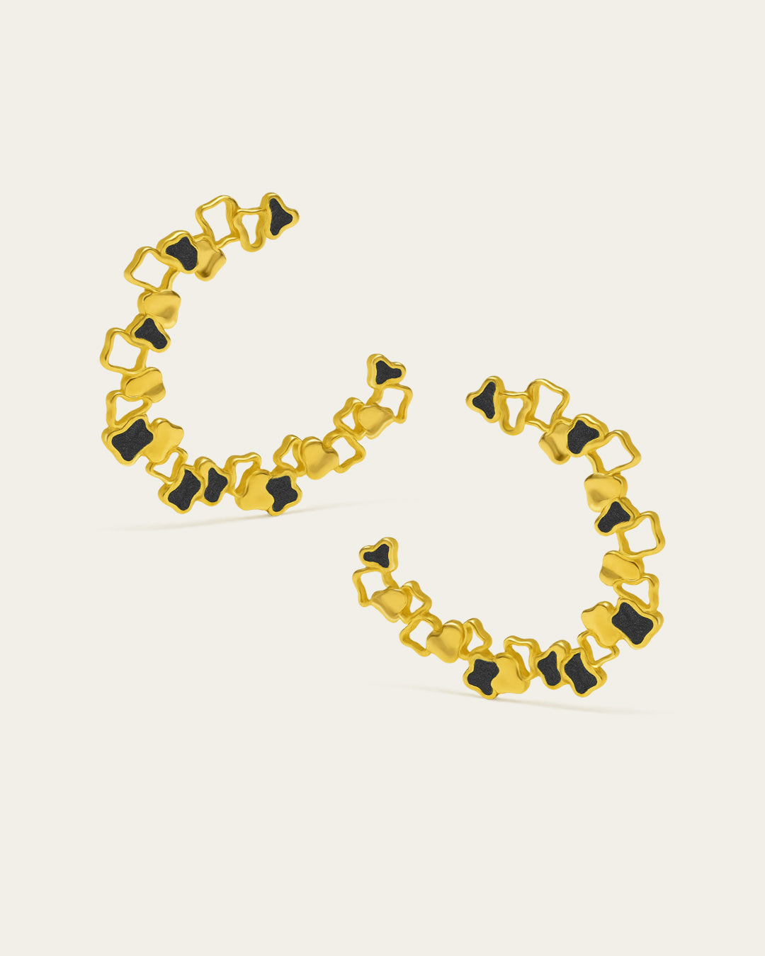 Statement gold Ripple hoop earrings with a textured, open-work design and black enamel accents.