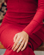 woman wearing a red sweater with a hand resting on their lap, wearing a sterling silver and 18k gold plated lotus, Ankh symbol ring representing eternal life with a hammered texture and polished edges