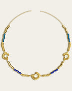 Glema necklace featuring earth-toned blue, baby blue resin and a central textured gold charm with a seahell stone