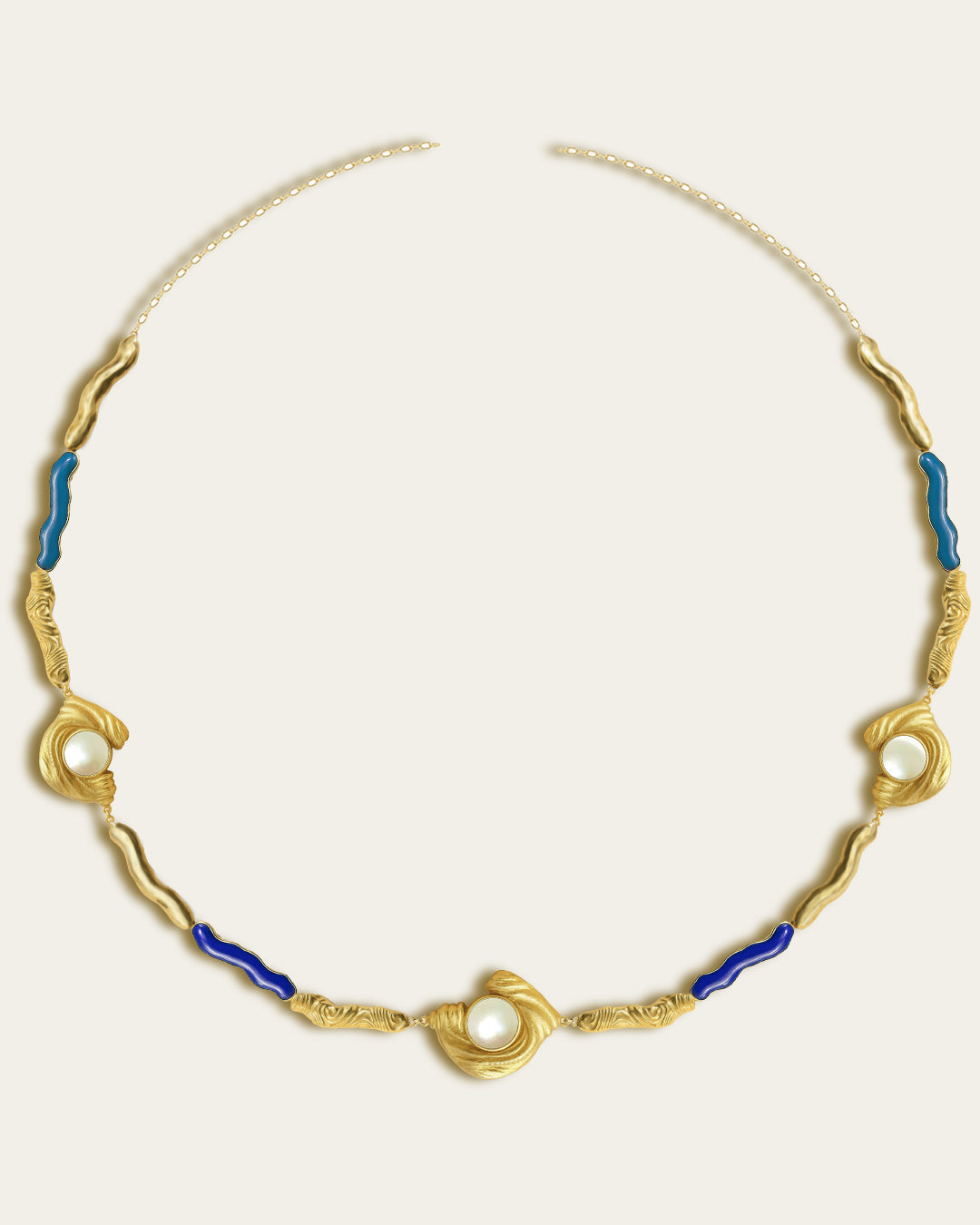 Glema necklace featuring earth-toned blue, baby blue resin and a central textured gold charm with a seahell stone