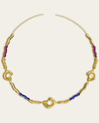 Glema necklace featuring earth-toned blue, magenta resin and a central textured gold charm with a seahell stone