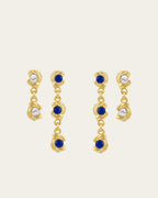 Mini Glema earrings stack in 18K gold-plated brass with blue stones and white seashell details, shown as a coordinated drop-earring bundle with built-in 15% discount.